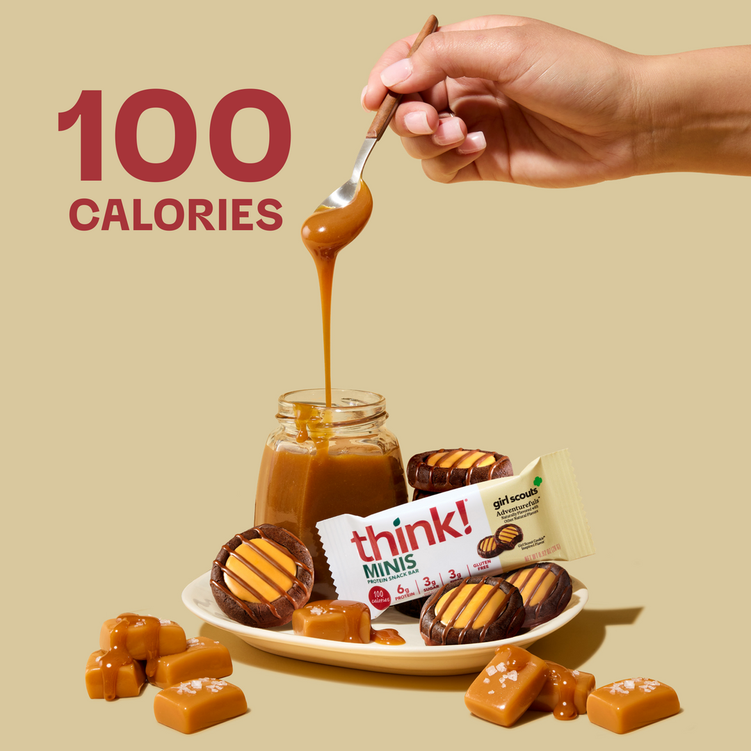 Caramel sauce being poured from a jar with 'think! MINIS' packaging and a hand holding a spoon.