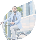 man in suit riding a bicycle with a building in the background